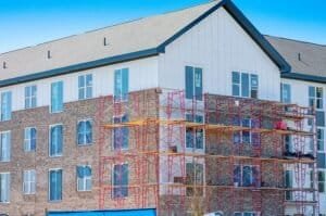 Horizontal shot of brick-layers scaffolding around a new multi-story apartment building.